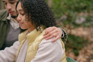 Concentrated busy crop ethnic couple hugging on blurred background of plants of park in daytime