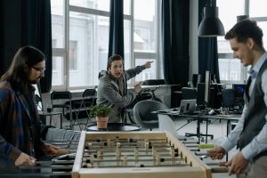 Young professionals engaged in a foosball game in a modern office, highlighting relaxation and teamwork.