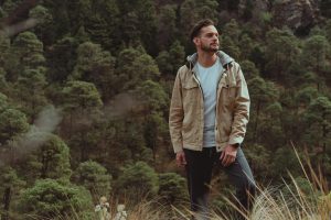 A man hikes through a lush forest, surrounded by greenery, enjoying the peaceful nature scenery.