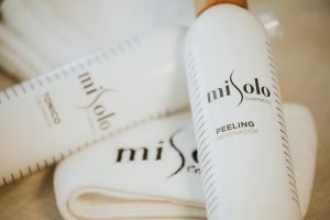 Close-up of MiSolo cosmetics skincare bottles and cloth for self-care.