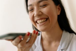 Close-up of a smiling young woman holding a smartphone indoors.