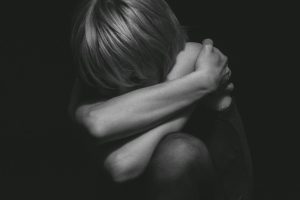 A dramatic black and white portrait capturing deep emotion and solitude in a studio setting.
