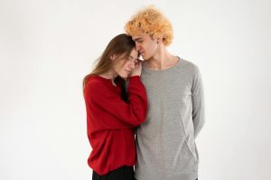 A young couple shares a tender moment in a minimalistic studio environment.