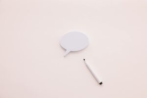 A minimalist speech bubble with a white marker on a clean white background, perfect for creative designs.