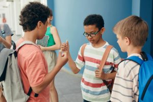 Children playing rock paper scissors outdoors, enjoying a fun school break together.