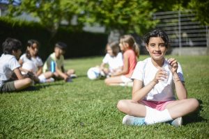 A group of children enjoying a sunny day outdoors in Portugal, sitting on the grass.