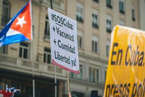 Protest in Cuba showcasing signs demanding more food, vaccines, and freedom.