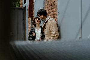 Stylish couple sharing an intimate moment in an urban setting with brick walls.