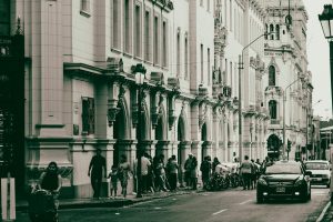 Street view of historic architecture with people and cars in a bustling city scene.