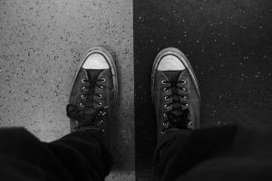 A pair of sneakers on contrasting black and white flooring.