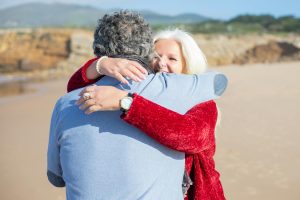 Affectionate elderly couple embracing on a sunny beach in Portugal.