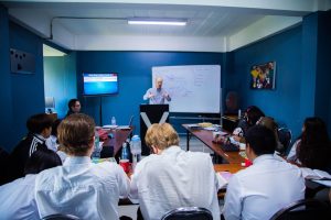 A business seminar with people attentively listening to a speaker in a modern classroom setting.