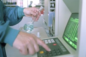 Close-up of a scientist operating lab equipment with a flask in hand.