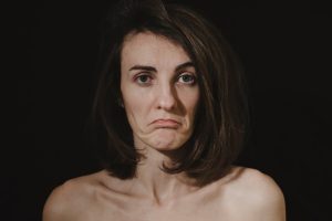 A melancholic portrait of a woman expressing sadness with a grumpy facial expression.