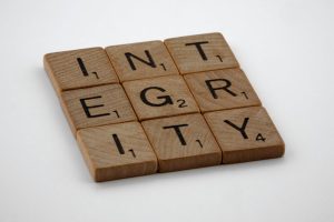 Wooden scrabble tiles spelling 'INTEGRITY' on a white background, emphasizing honesty and ethics.