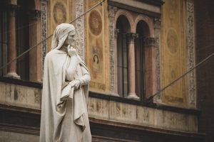 Statue of Dante Alighieri in front of historical building in Verona, Italy.