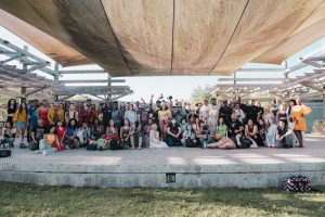 A diverse group of men and women posing outdoors under a wooden structure in Orlando, FL.