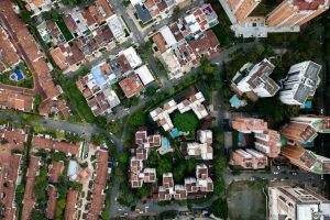High-angle drone shot capturing an urban neighborhood with residential buildings and pools.