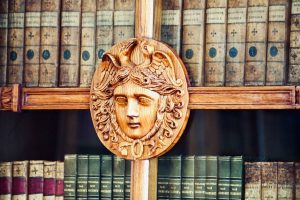 Intricate wooden sculpture adorning a bookshelf with classic literature.