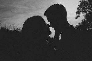 Silhouette of a couple sharing a romantic moment in nature with a moody atmosphere.