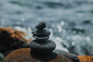 Peaceful stack of stones on a beach with ocean waves in the background, symbolizing balance and tranquility.