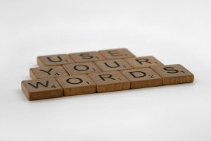 Close-up of wooden letter tiles spelling 'Use Your Words' on a white background, perfect for communication and language themes.