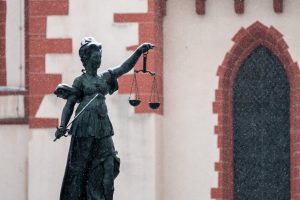 A statue of Lady Justice in an urban area during snowfall.