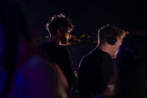 Two DJs wearing headphones performing at a nighttime event in Sozopol, Bulgaria.
