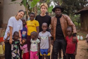 A joyful group of adults and children embracing cultural diversity and unity in an outdoor setting.
