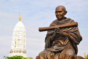 A serene bronze Buddha statue next to an elegant white pagoda, symbolizing spirituality and tradition.