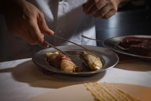 Chef arranging a gourmet dish with precision in a dimly lit kitchen.