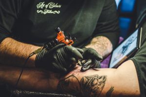 Tattoo artist creating detailed design on arm in studio setting.
