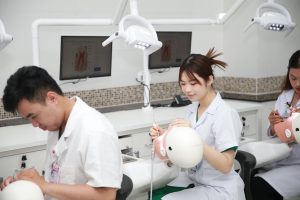 Dental students practicing procedures on training models in a classroom setting.
