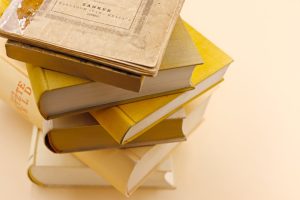 A collection of antique books stacked on a warm cream background, showcasing vintage charm and historical intrigue.