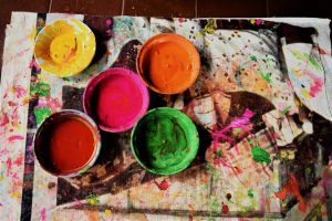 Vibrant bowls of paint in various colors on a splattered canvas, perfect for creative projects.