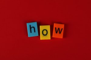 Colorful letter tiles spelling 'How' on a vibrant red background, ideal for educational content.