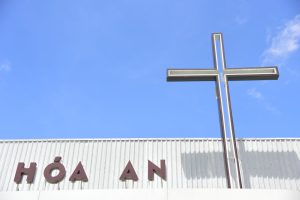 A church building with a prominent cross structure and clear blue sky background.