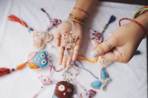 Vibrant handmade fabric ornaments including butterflies and hearts on display with hands holding them.