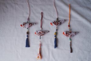 Four handmade bird-shaped ornaments laid out on a soft fabric surface.