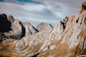 Captivating view of rugged mountain peaks casting shadows under a partially cloudy sky, showcasing nature's grandeur.