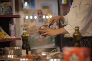 A chef carefully preparing a meal in a warmly lit, cozy restaurant kitchen setting.