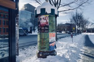 Snow-covered street with a cylindrical advertisement pillar on a winter day.