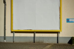 Empty billboard on a street with yellow frame, perfect for advertisement mockup.