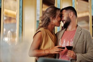 Young couple enjoying a romantic moment with red wine indoors.