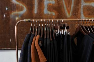 Modern clothing rack in a boutique with diverse garments and wooden hangers