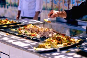 Chef adds spices to sizzling meat and vegetables at a vibrant street food stall.