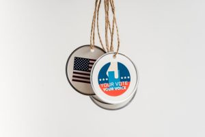 Close-up view of USA voting badges hanging on strings against a white background.