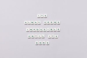 Motivational quote 'It always seems impossible until it's done' in Scrabble tiles.