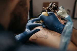 Detailed image of a tattoo artist creating intricate skin art with a tattoo machine.