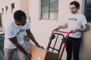 Volunteers in white shirts working together loading boxes onto a cart for distribution.